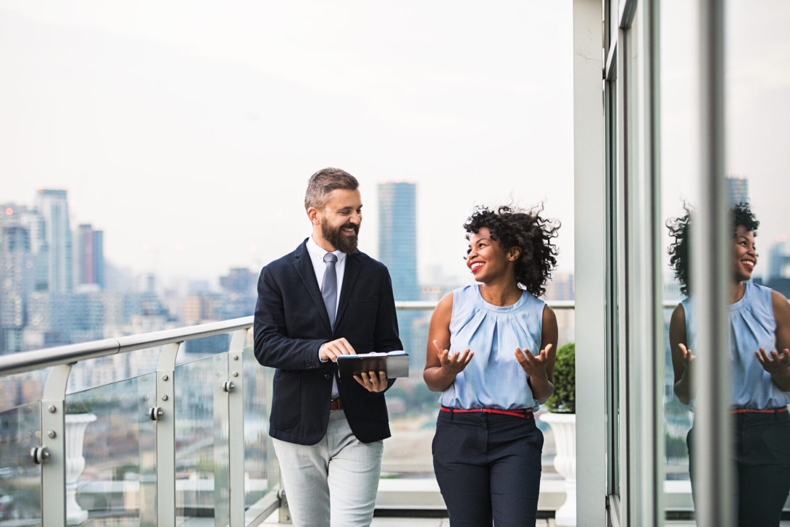 A portrait of businesspeople standing against London rooftop view, discussing something.