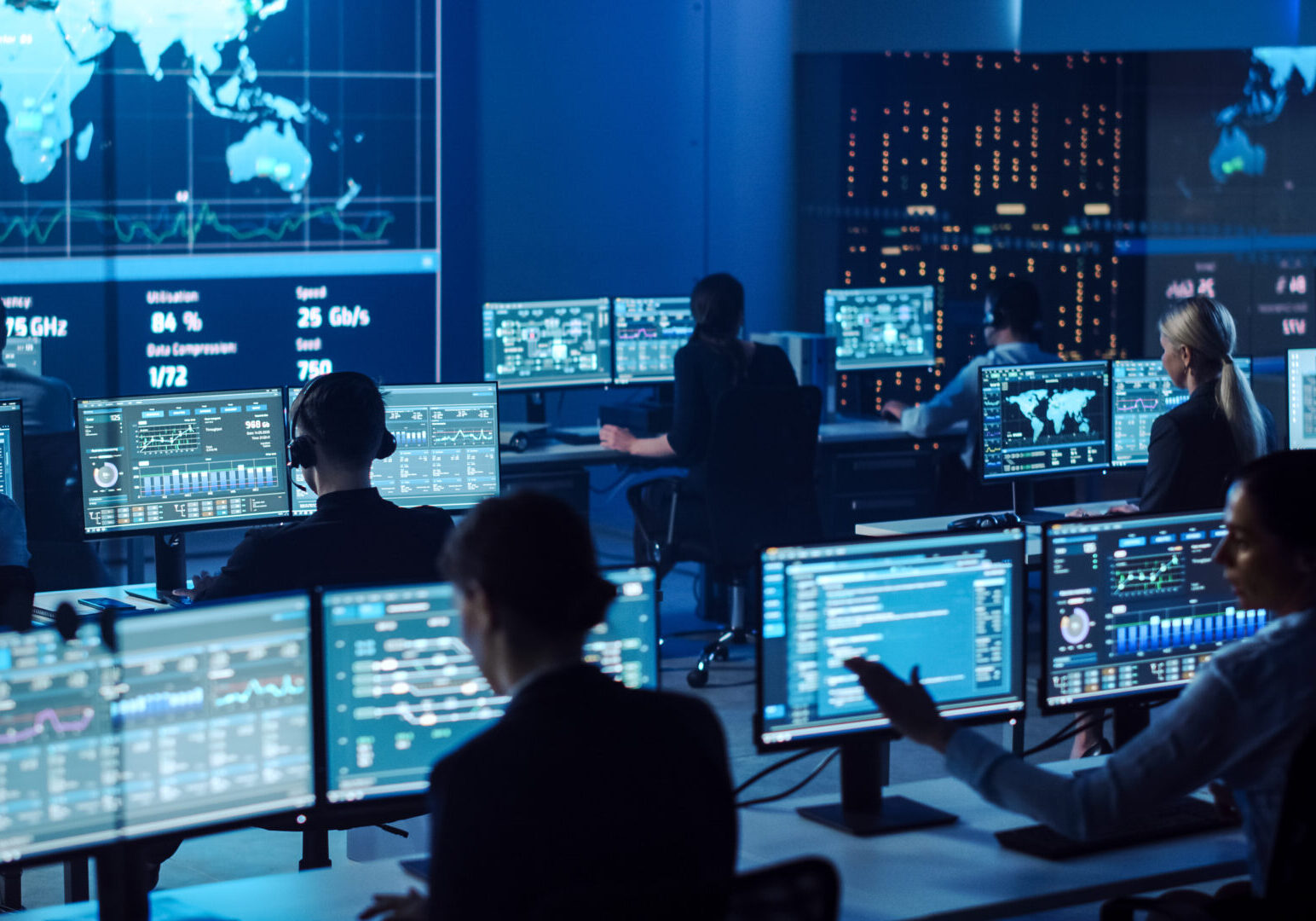 Team of Professional Computer Data Science Engineers Work on Desktops with Screens Showing Charts, Graphs, Infographics, Technical Neural Network Data and Statistics. Dark Control and Monitoring Room.