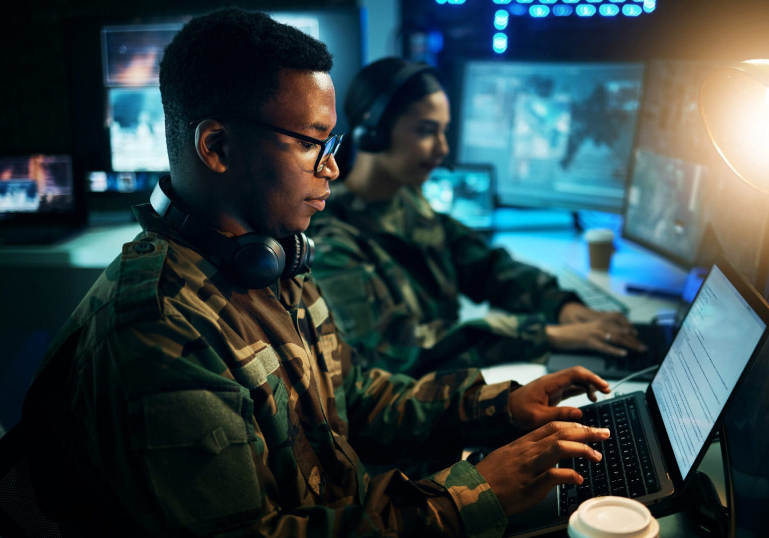 Military control room, computer and soldier at desk, typing code and tech for communication army office. Security, global surveillance and black man at laptop in government cyber data command center